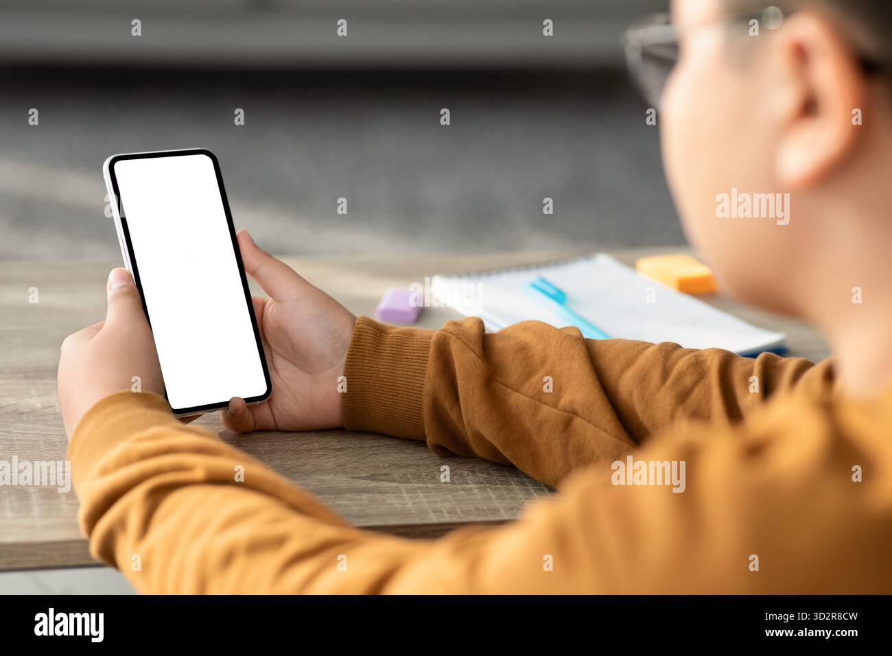 Chubby Boy Using Smartphone During Homework in Cozy Home Setting Stock Photo