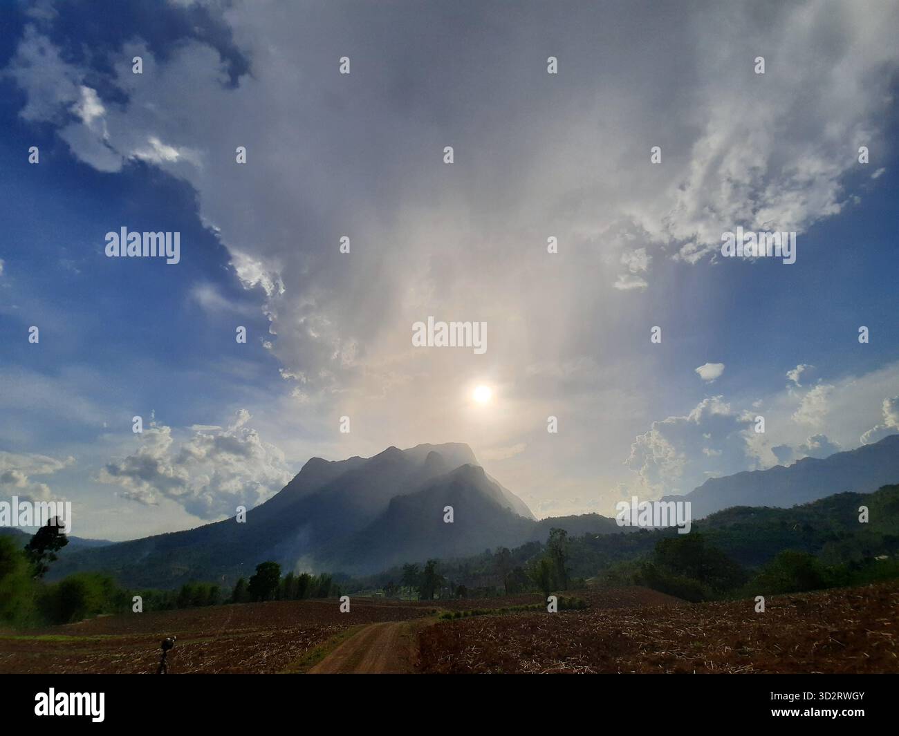Dramatic sky over majestic mountain peak at sunrise brings sense of awe and tranquility, with sunrays breaking through clouds creating breathtaking na Stock Photo