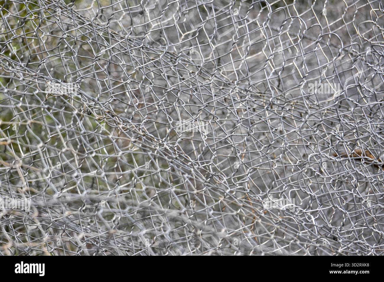 Metallic wire mesh texture forms an intricate grey background pattern, feeling of enclosure Stock Photo