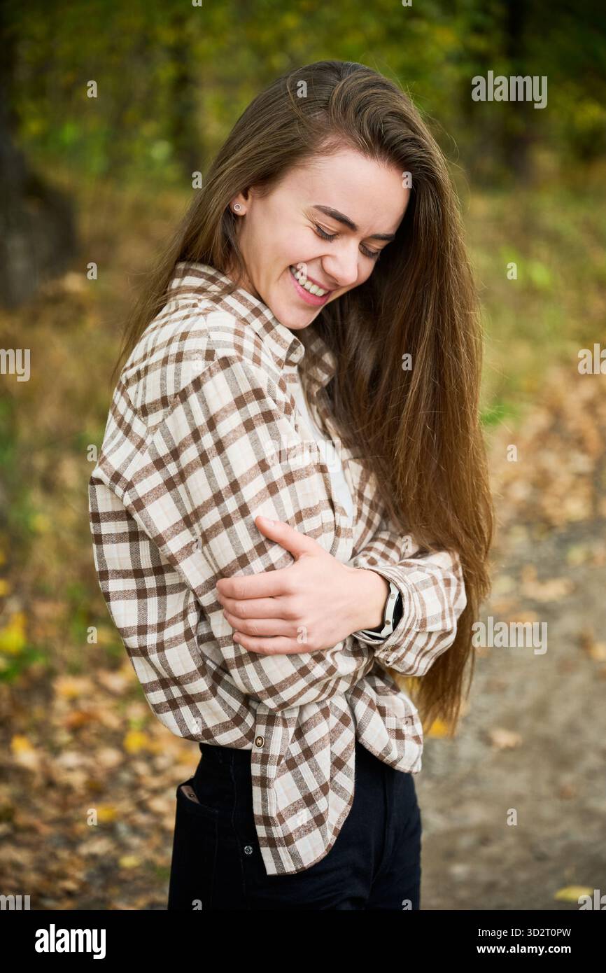 A young woman with long hair smiles warmly while standing in a colorful ...
