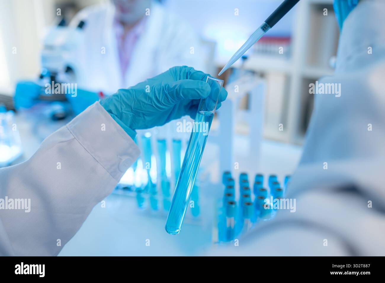Two female scientists in white lab coats working together in a bright ...