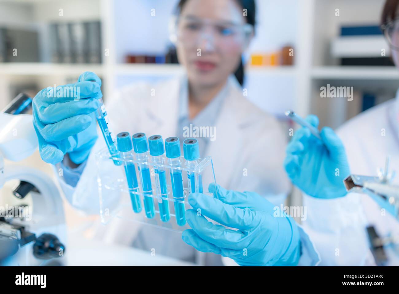Two female scientists in white lab coats working together in a bright ...