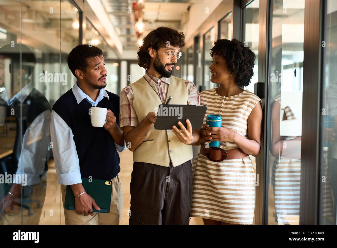 Coworkers discussing project using digital tablet in office hallway Stock Photo