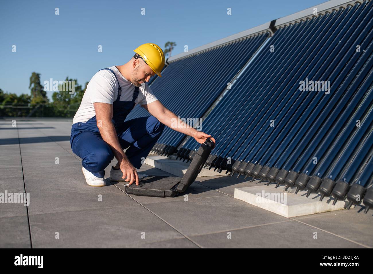 Technician using tool case examining solar power equipment Stock Photo
