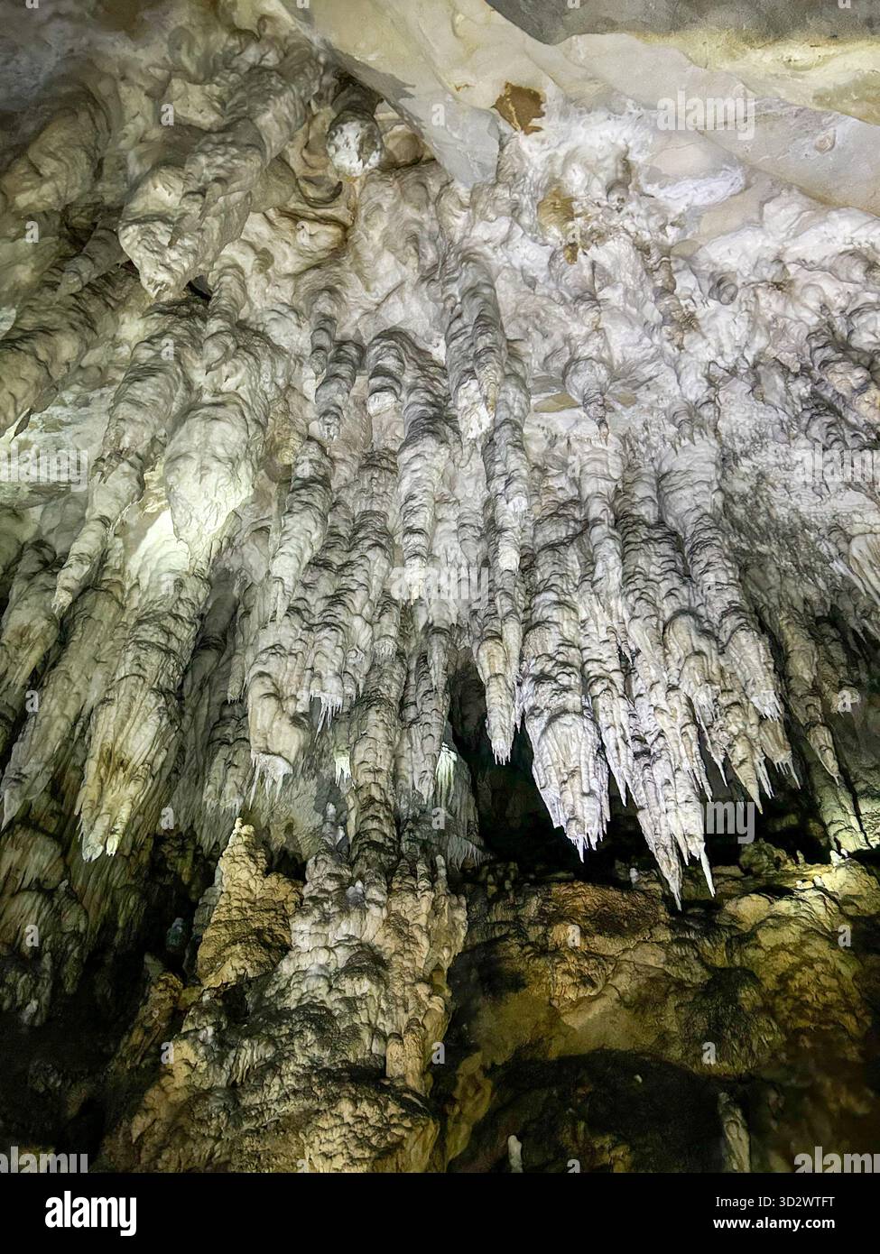 Close-up view of stalactites and rock formations inside a limestone cave, revealing stunning natural textures shaped by centuries of mineral deposits. - Smartphone Captured Stock Image
