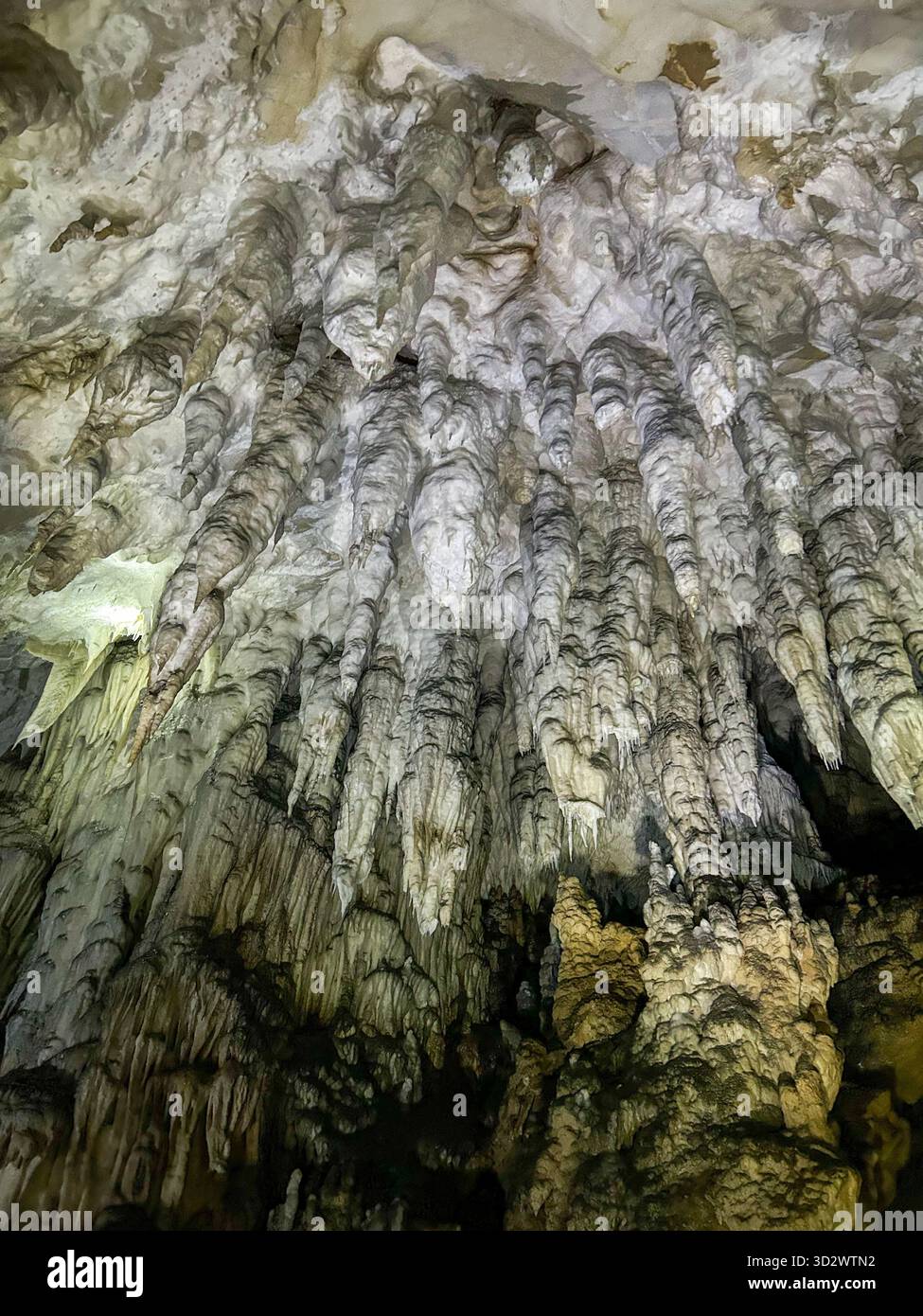 Close-up view of dramatic stalactites and limestone textures inside the Ice Cave in Uvac Canyon, Serbia, illuminated by artificial light. - Smartphone Captured Stock Image