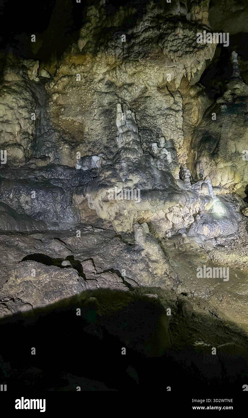 Detailed view of stalagmites and mineral deposits inside a dark limestone cave, highlighting the unique textures created by slow natural processes. - Smartphone Captured Stock Image