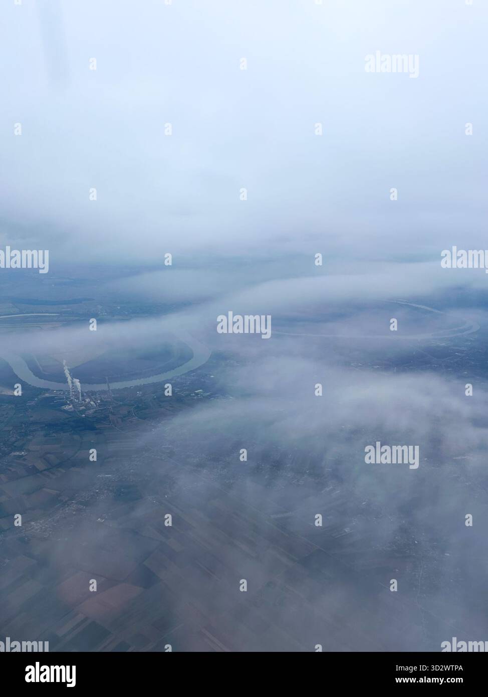 A serene aerial view of winding rivers and fields partly veiled by soft clouds, capturing the calm beauty of nature from above. - Smartphone Captured Stock Image