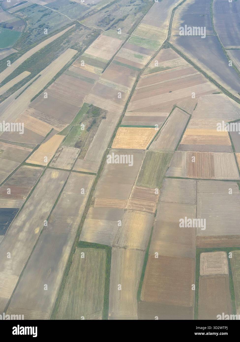 Aerial photo showing geometric agricultural fields with different shades of brown and green, forming abstract patterns on the landscape. - Smartphone Captured Stock Image