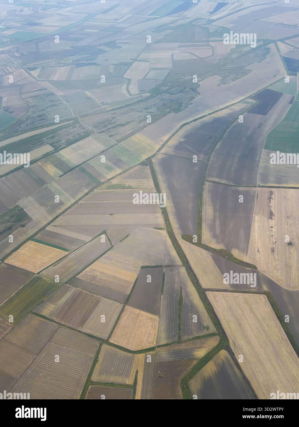 Drone or airplane view of rural agricultural land divided into geometric parcels with visible plowed soil. - Smartphone Captured Stock Image