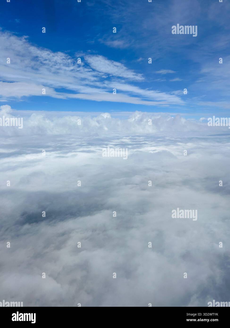 Aerial view of soft white clouds and vivid blue sky taken from an airplane window, showing peaceful layers of clouds and clear atmosphere. - Smartphone Captured Stock Image
