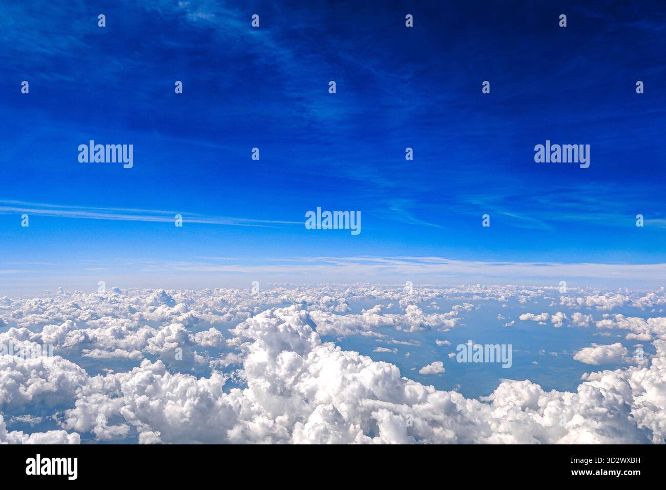 Aerial view of white fluffy clouds in deep blue sky. View from airplane ...