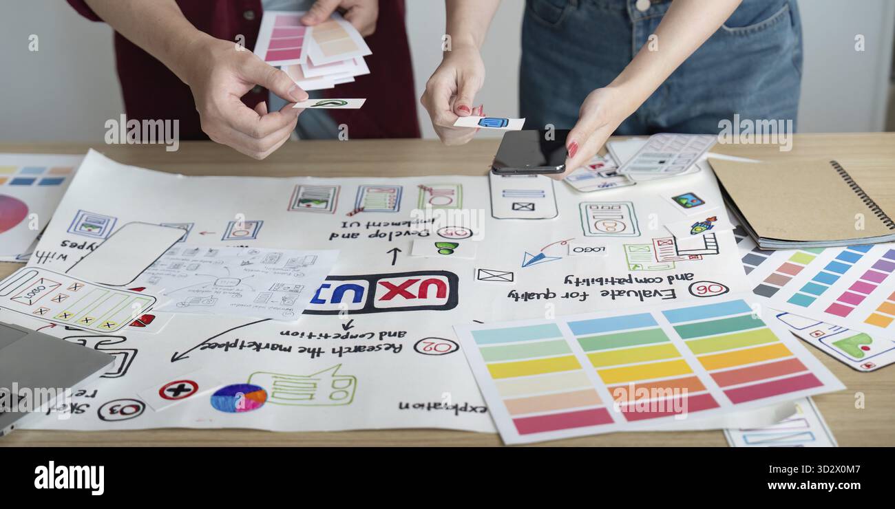 A creative team collaborates on design concepts, sharing ideas and feedback while reviewing project materials on a table Stock Photo