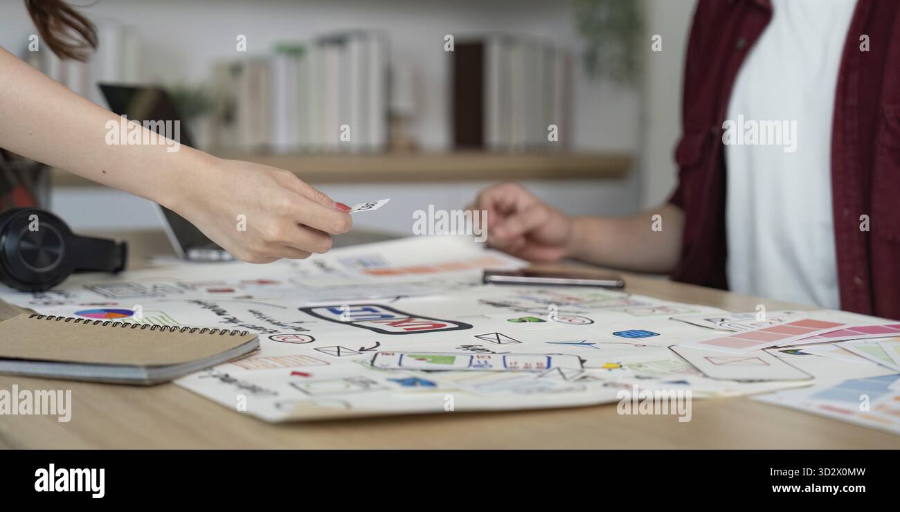 A creative team collaborates on design ideas, sharing feedback and materials in a modern workspace Stock Photo