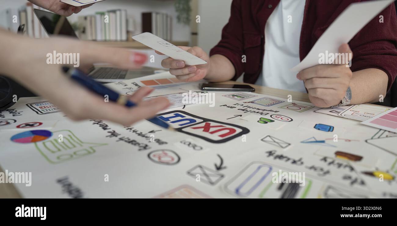 Designers analyzing user experience concepts and interface designs, highlighting teamwork and innovation in a collaborative setting Stock Photo