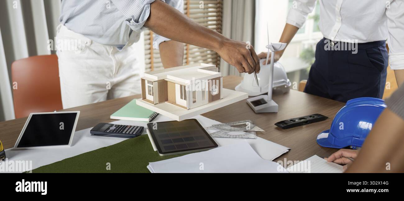 Engineers working at their workstation, skillfully finalizing innovative project designs using high-tech tools and models focused on sustainability Stock Photo