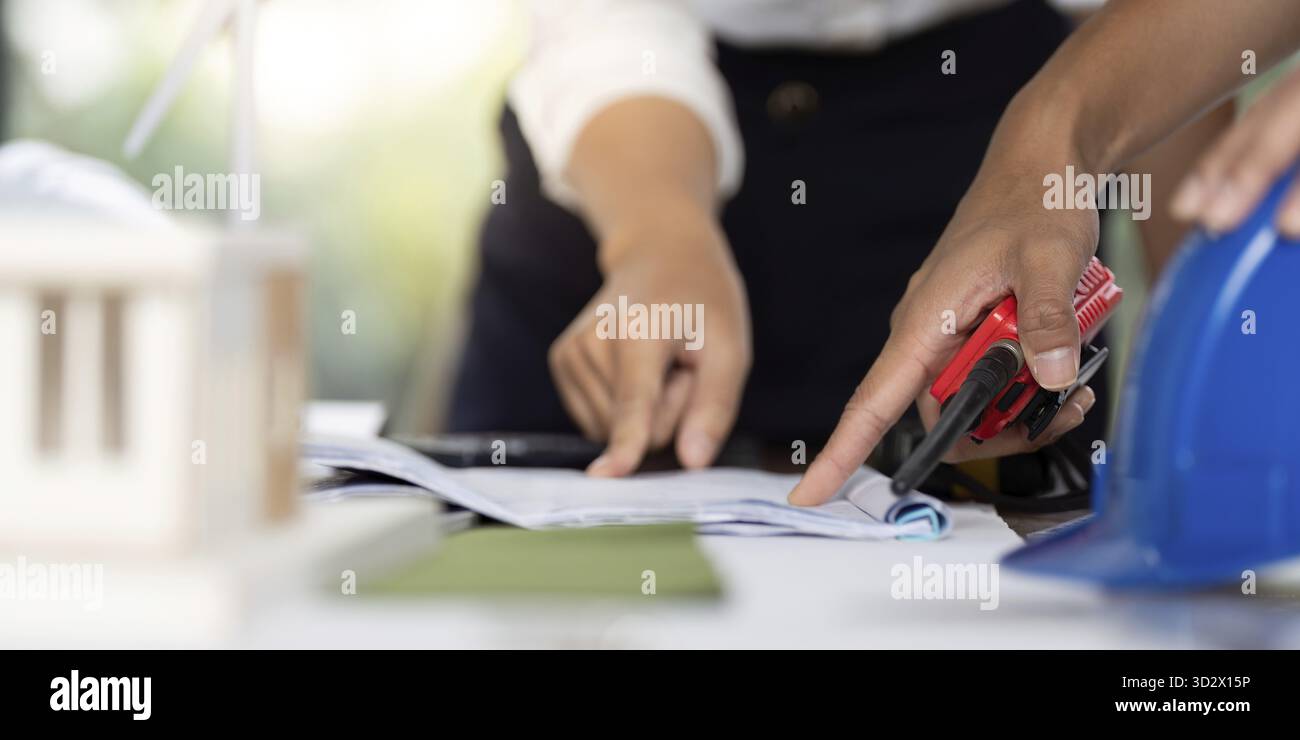 Engineers collaborating on construction plans and designs, using tools and materials for developing sustainable building projects Stock Photo