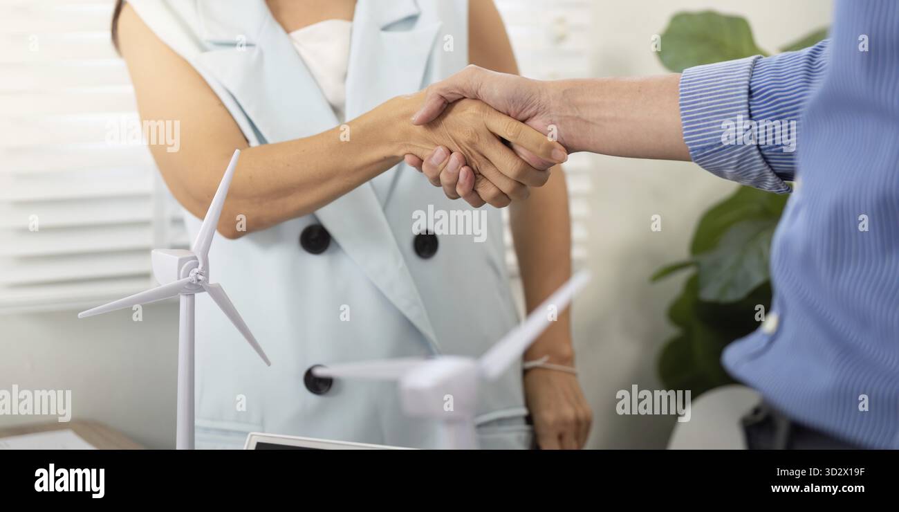 A handshake between two colleagues symbolizes a partnership for sustainability in their workplace, emphasizing collaboration and commitment Stock Photo