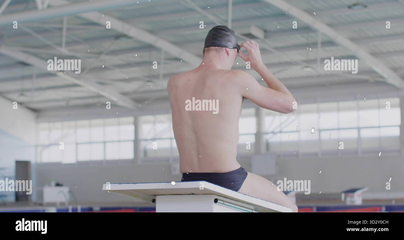 Adjusting swim goggles male swimmer sitting on diving bench at lap pool ...