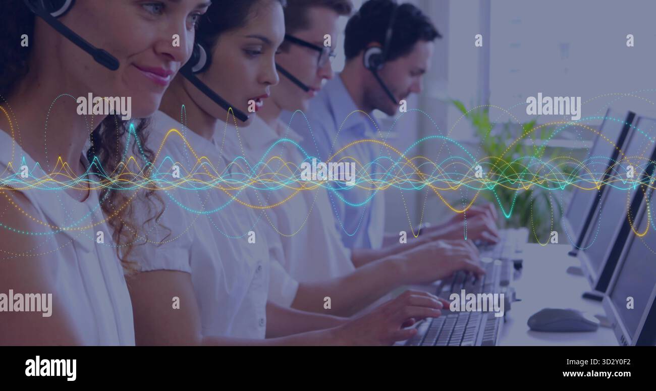 Typing call center agents wearing headsets at office desk, with ...
