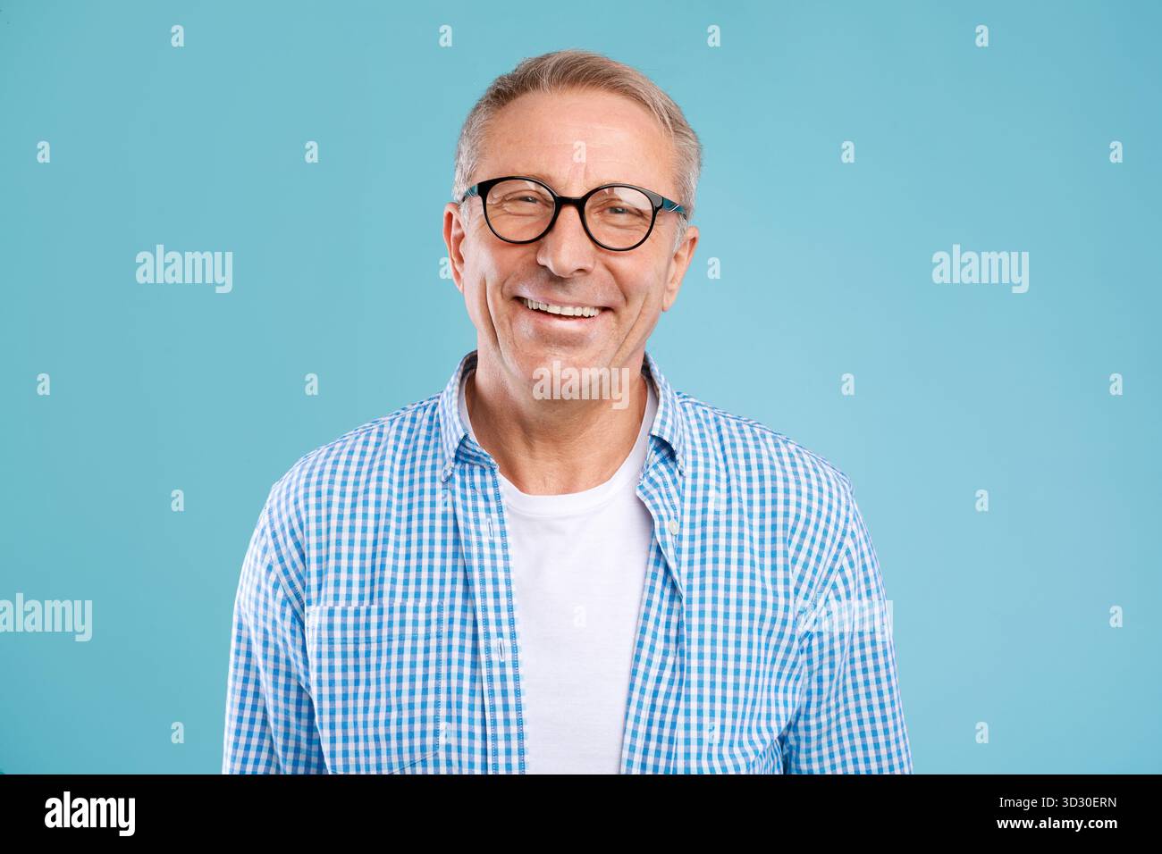 Smiling Mature Man in Glasses Posing in a Studio With Blue Background Stock Photo