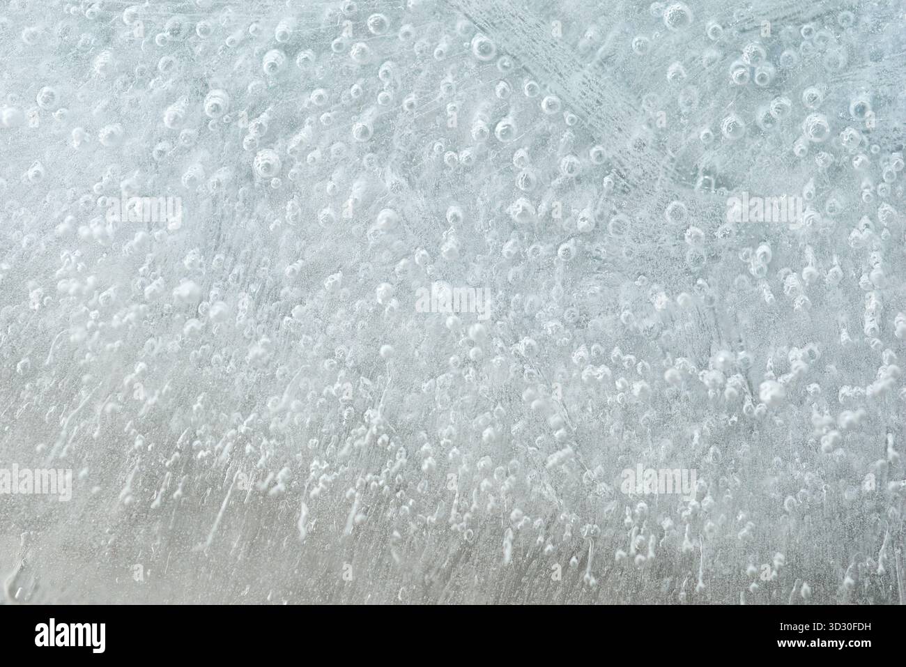 Frost develops unique, delicate patterns on a glass surface viewed from inside. The artwork showcases tiny ice formations and bubbles reflecting light Stock Photo