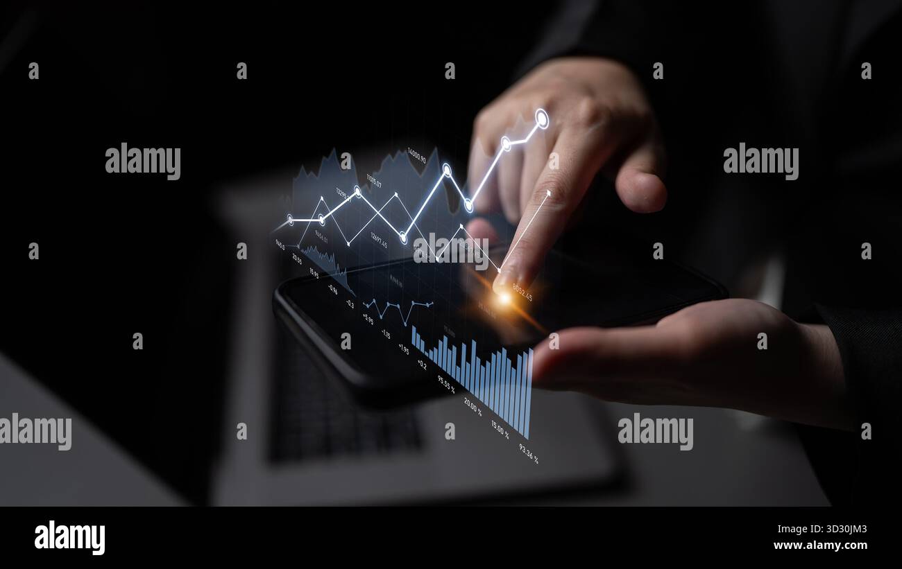 A professional hand interacts with a sleek smartphone displaying dynamic financial graphs and analytics, symbolizing data-driven decision making and m Stock Photo