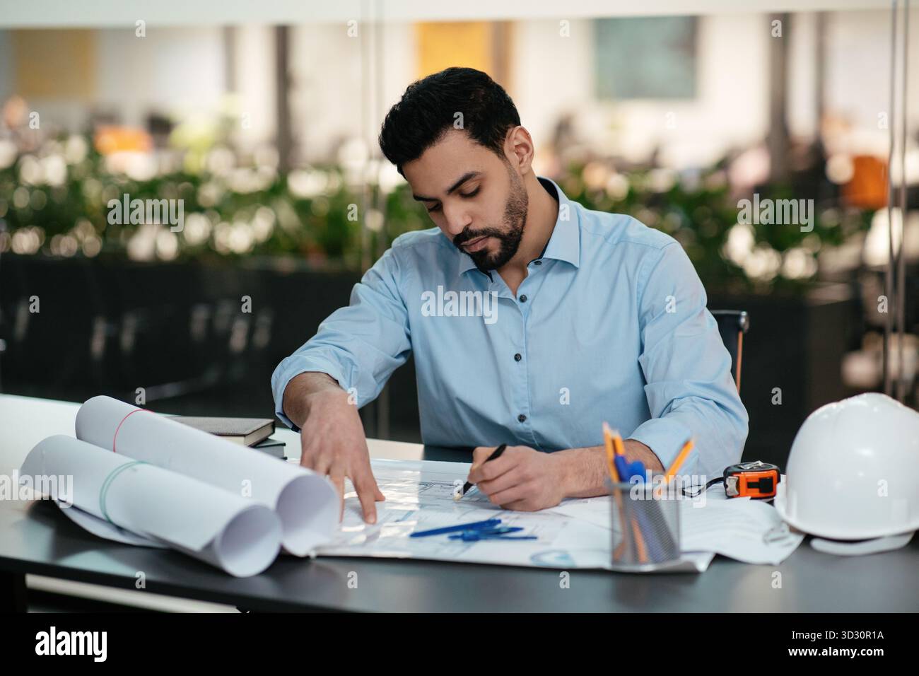 Engineer Working on Blueprint Designs in a Modern Office Space During ...