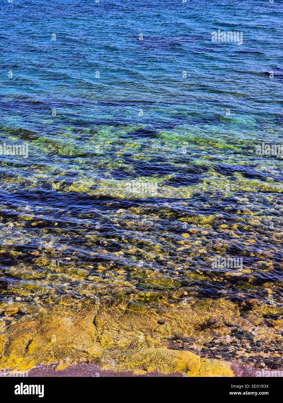 Crystal Clear Blue Water Over Pebbles and Rocks on the Coast. - Smartphone Captured Stock Image