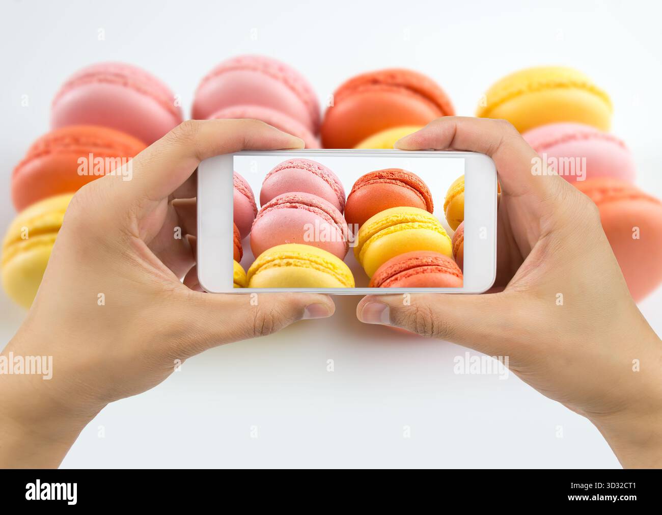 hand with smartphone photographing a plate of macarons for upload to internet Stock Photo
