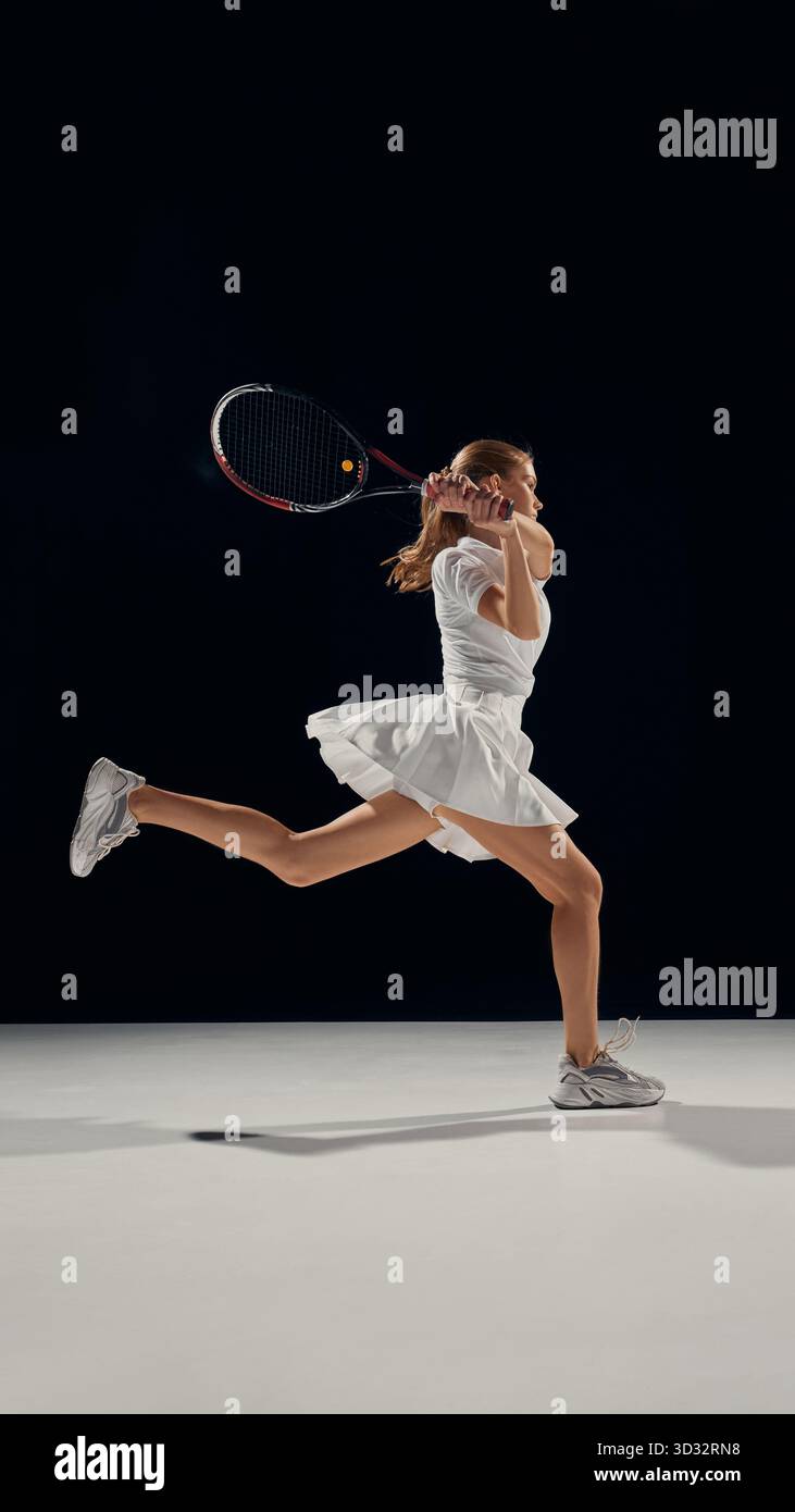Female tennis player in white uniform hitting backhand shot with ...