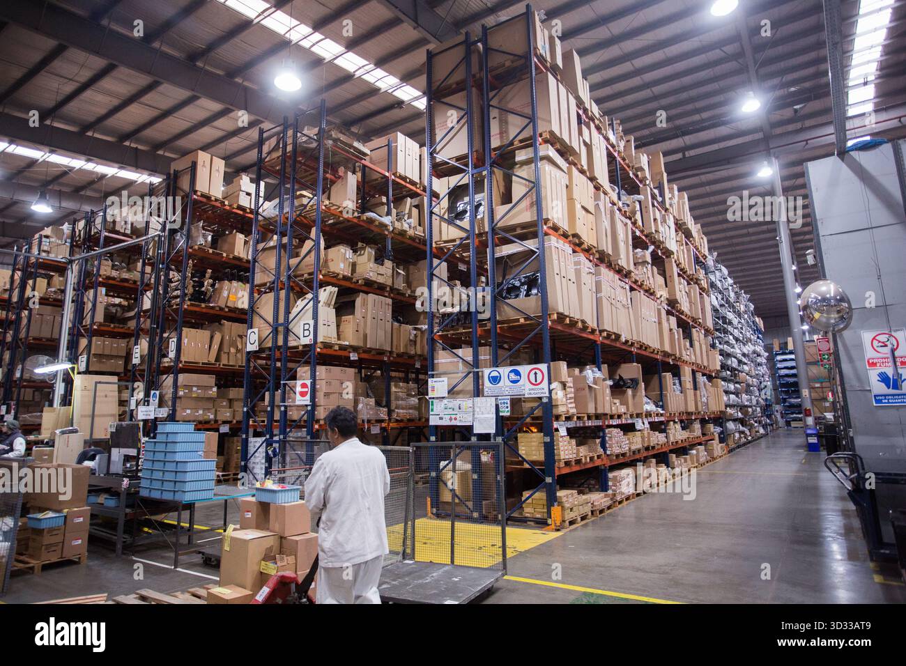 Men at work, wearing protective stuff, handling boxes in a warehouse Stock Photo