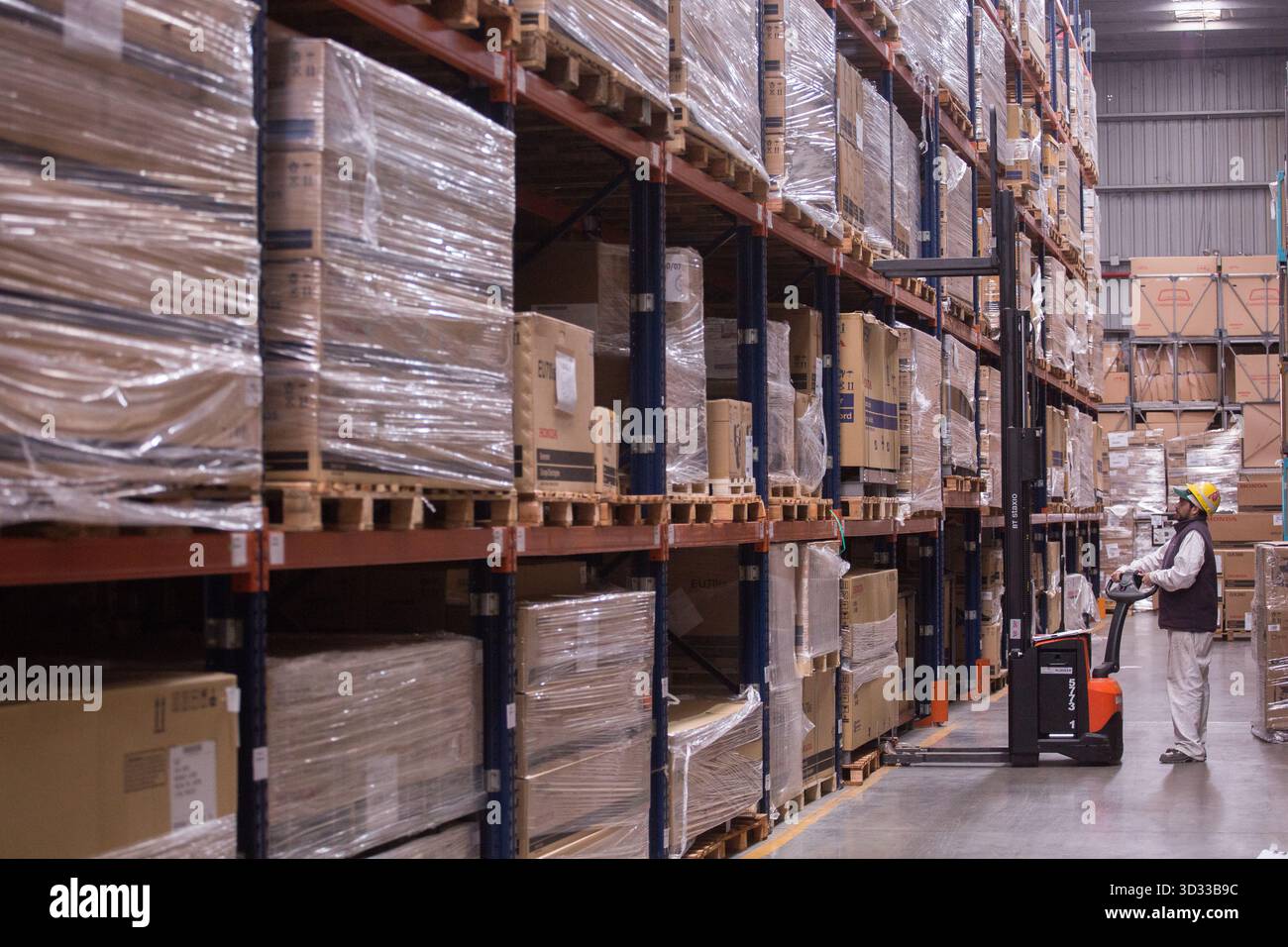 Men at work, wearing protective stuff, handling boxes in a warehouse Stock Photo