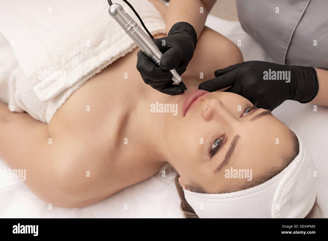 Cosmetologist applying permanent make up on the lips Stock Photo
