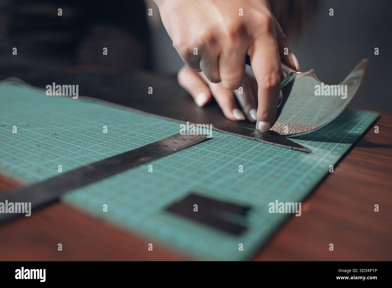 Tanner female hands cutting leather goods on workshop. Working process of leather craftsman Stock Photo