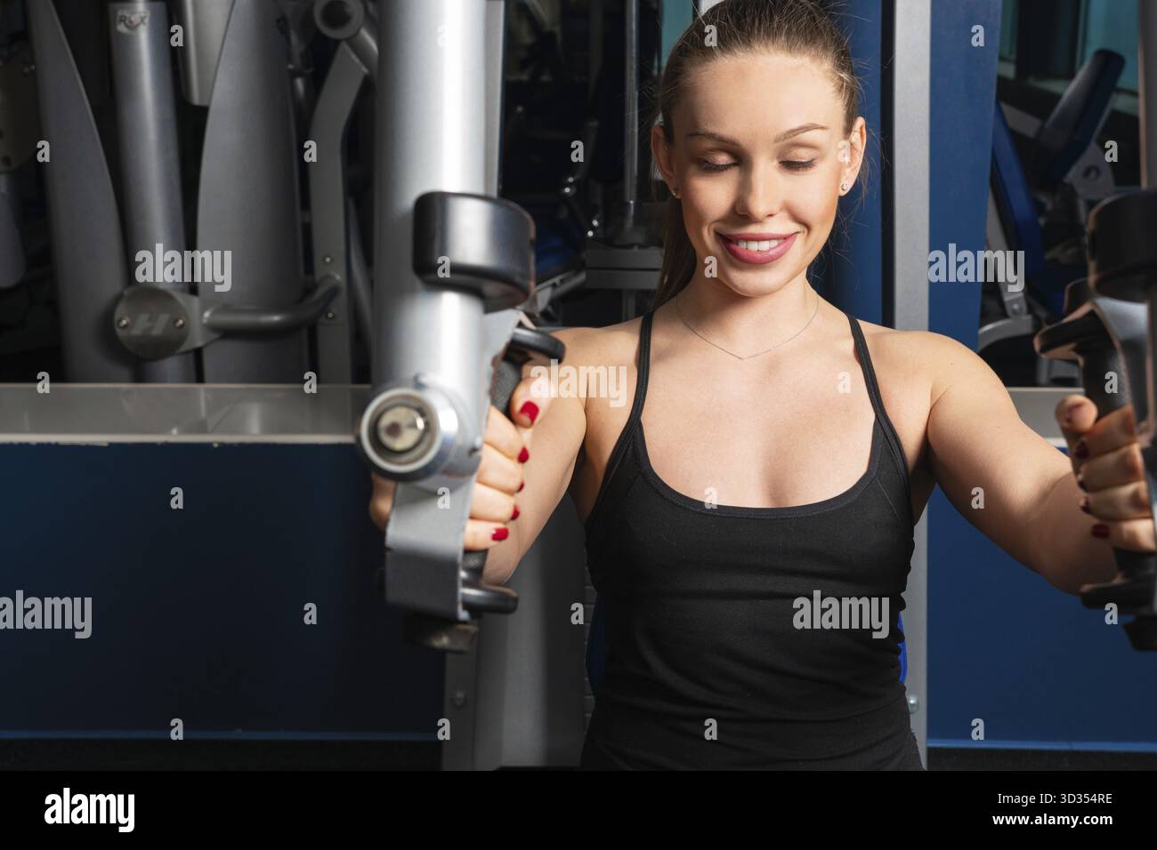 Young fitness woman execute exercise with machine in a gym Stock Photo