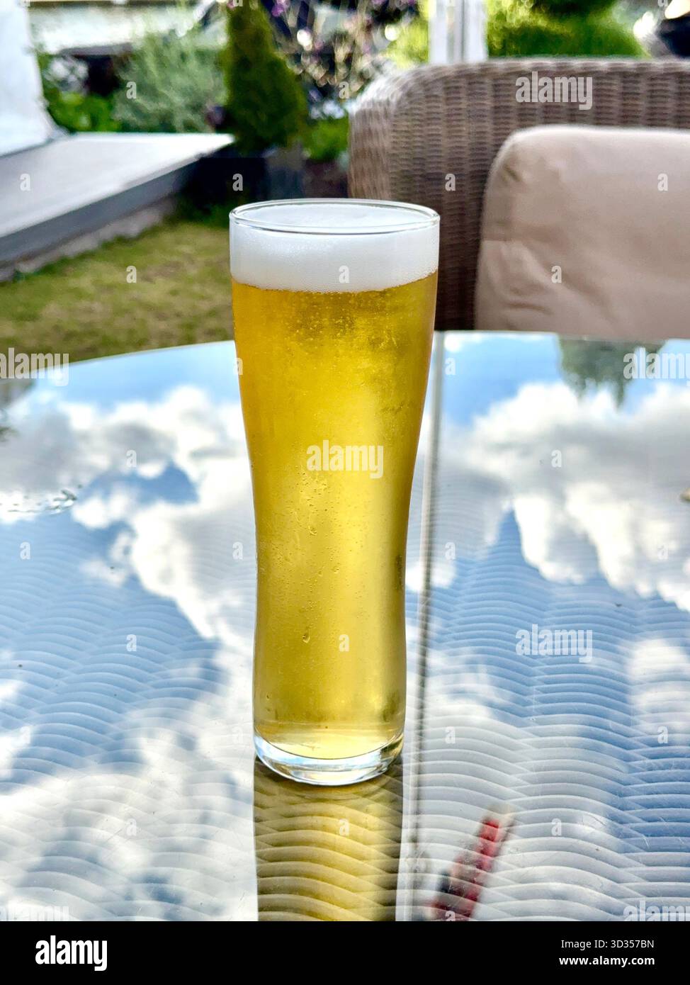 Pint glass of cold golden lager beer on a table in the garden of a luxury hotel. No people. - Smartphone Captured Stock Image