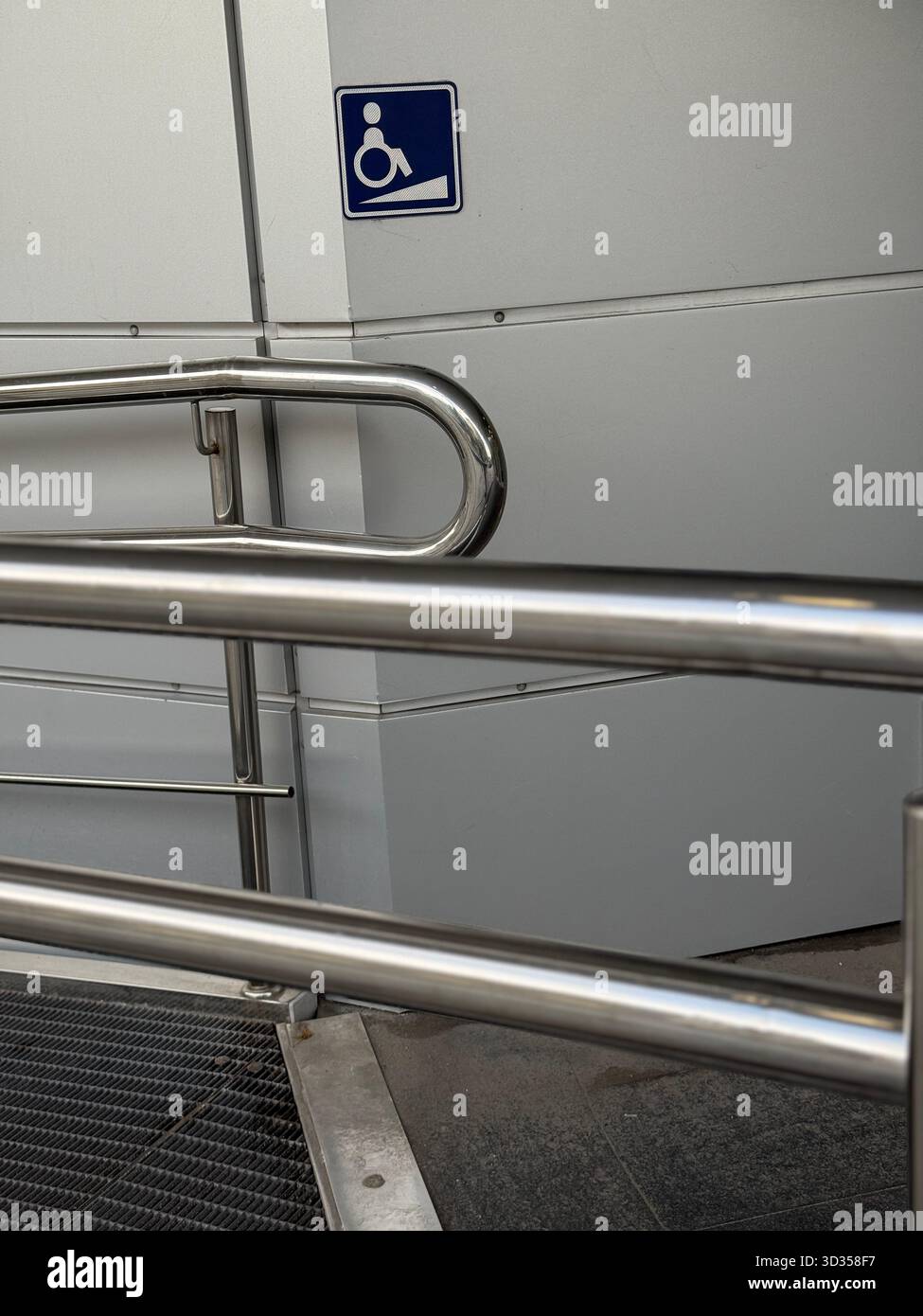 Accessible ramp with stainless steel railings beside a wall indicating ...