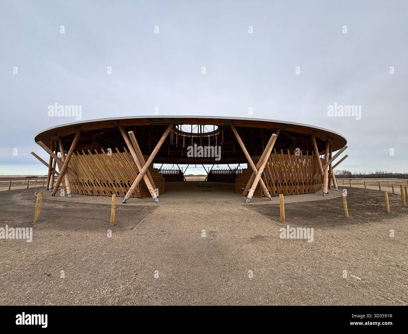 Timber amphitheatre with sweeping wooden roof and tiered seating on an indigenous reserve, set against vast prairies, symbolizing sustainable design. - Smartphone Captured Stock Image