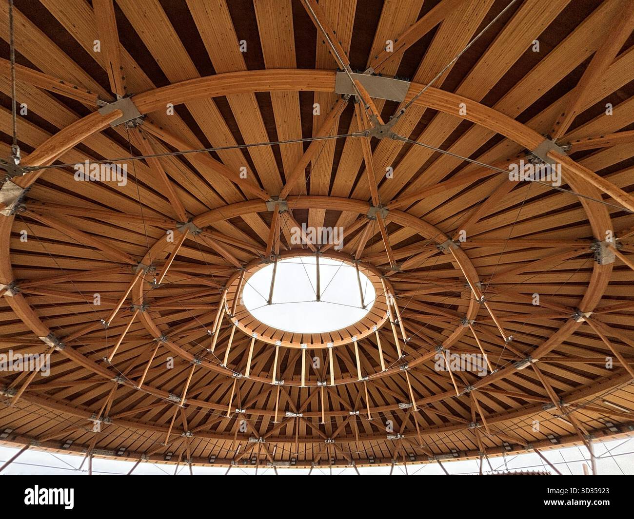 Timber amphitheatre with sweeping wooden roof and tiered seating on an indigenous reserve, set against vast prairies, symbolizing sustainable design. - Smartphone Captured Stock Image