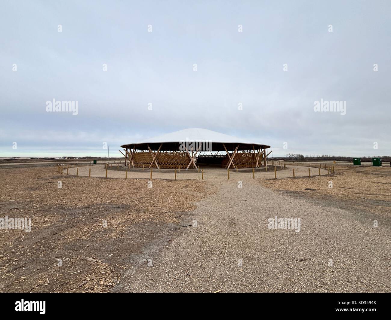 Timber amphitheatre with sweeping wooden roof and tiered seating on an indigenous reserve, set against vast prairies, symbolizing sustainable design. - Smartphone Captured Stock Image