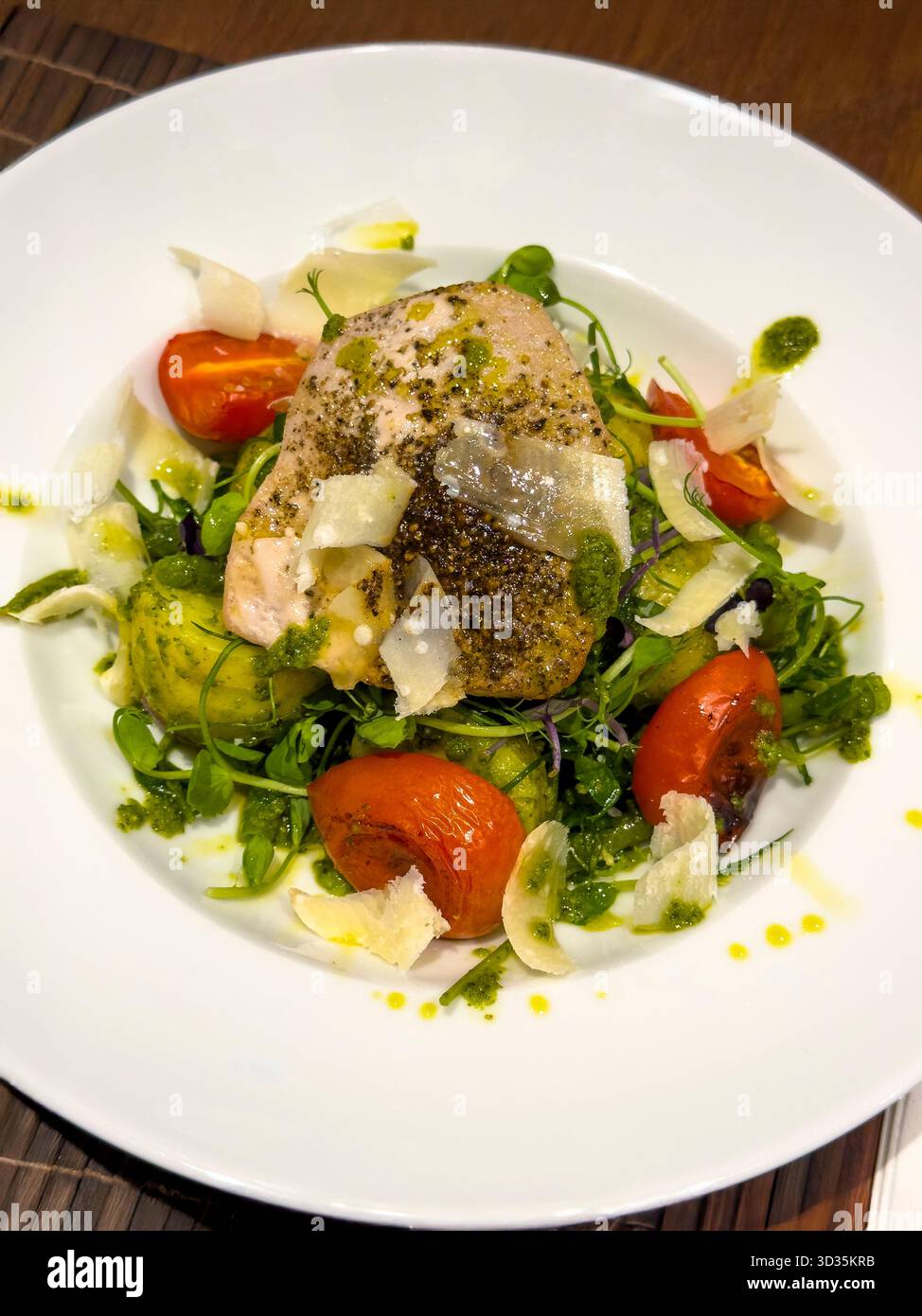 Tuna Steak en Papillote Served on a Potato, Green Bean, Tomato and Rocket Salad with Basil Pesto and Parmesan shavings in a White Bowl - Smartphone Captured Stock Image
