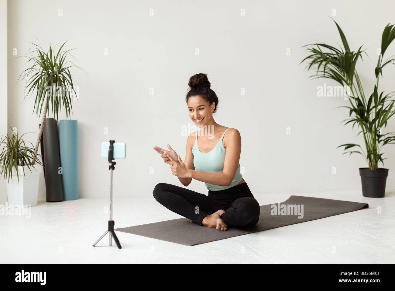 Smiling Female Yoga Instructor Records Video Tutorials in a Bright Studio Setting Stock Photo