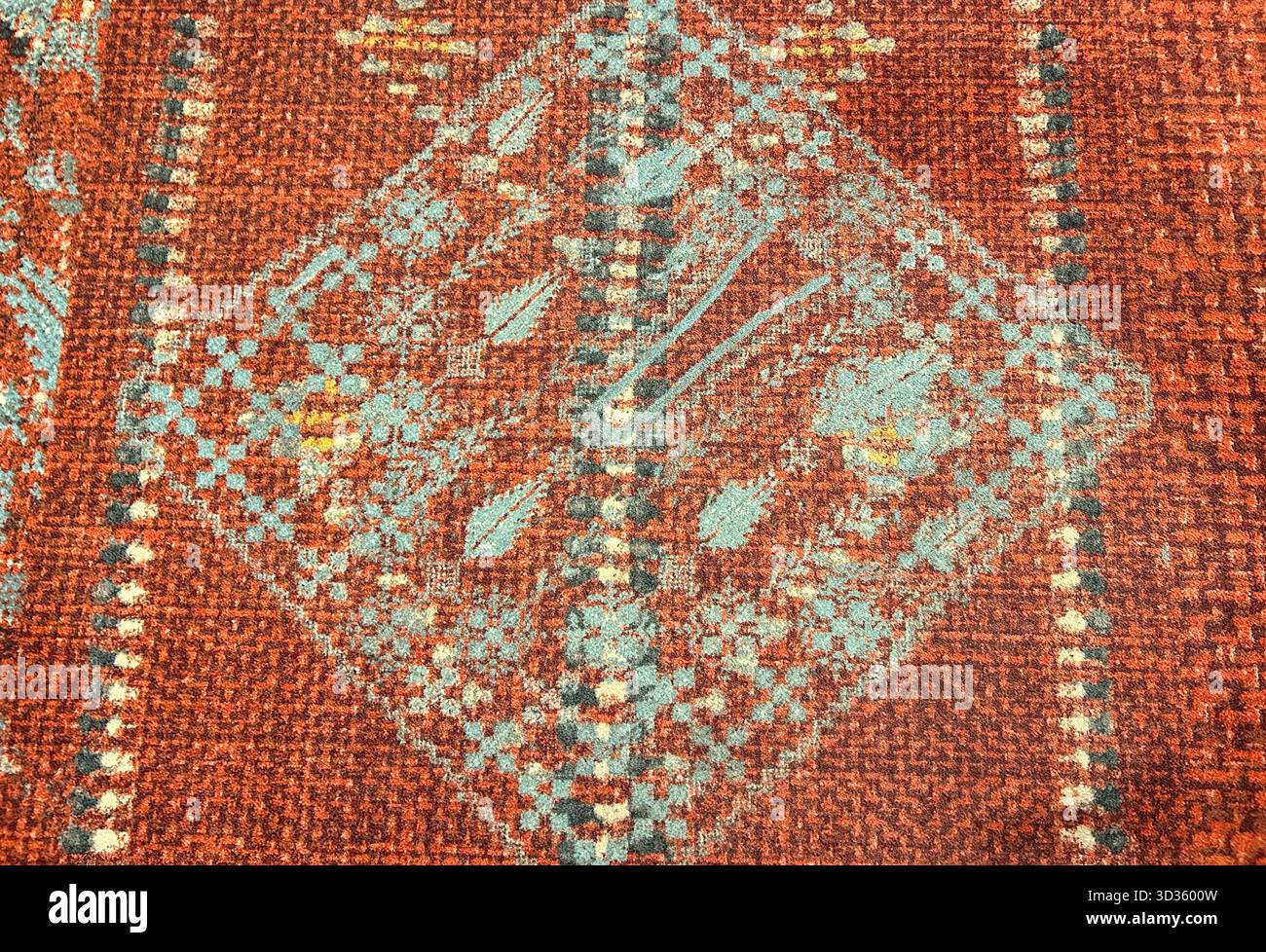 Close-up of a traditional woven carpet with geometric motifs in red and turquoise tones, showing rich texture and intricate ethnic design. - Smartphone Captured Stock Image