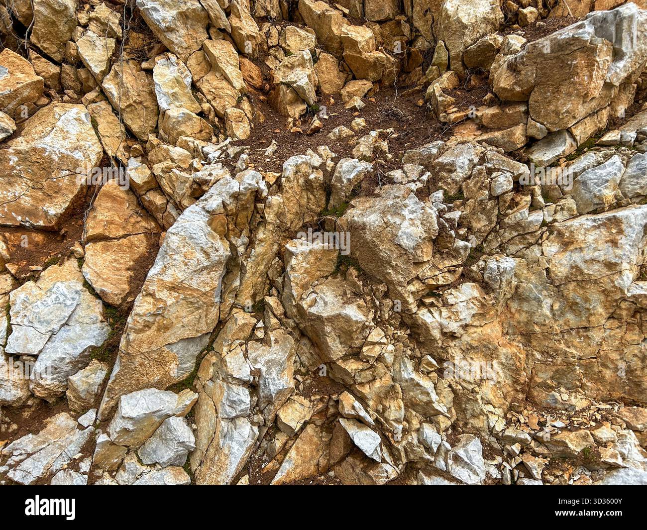 Close-up view of a rugged rock surface showing natural fractures, layers, and earthy tones. Perfect for geology, nature, or texture backgrounds. - Smartphone Captured Stock Image