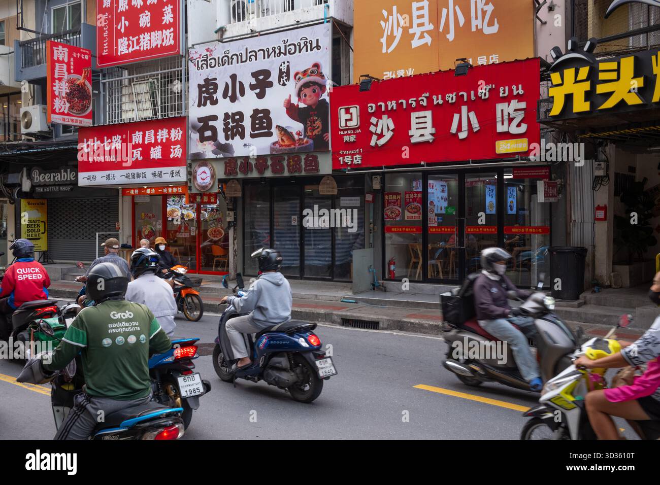 Motorcyclists pass by various Chinese restaurants. Stock Photo