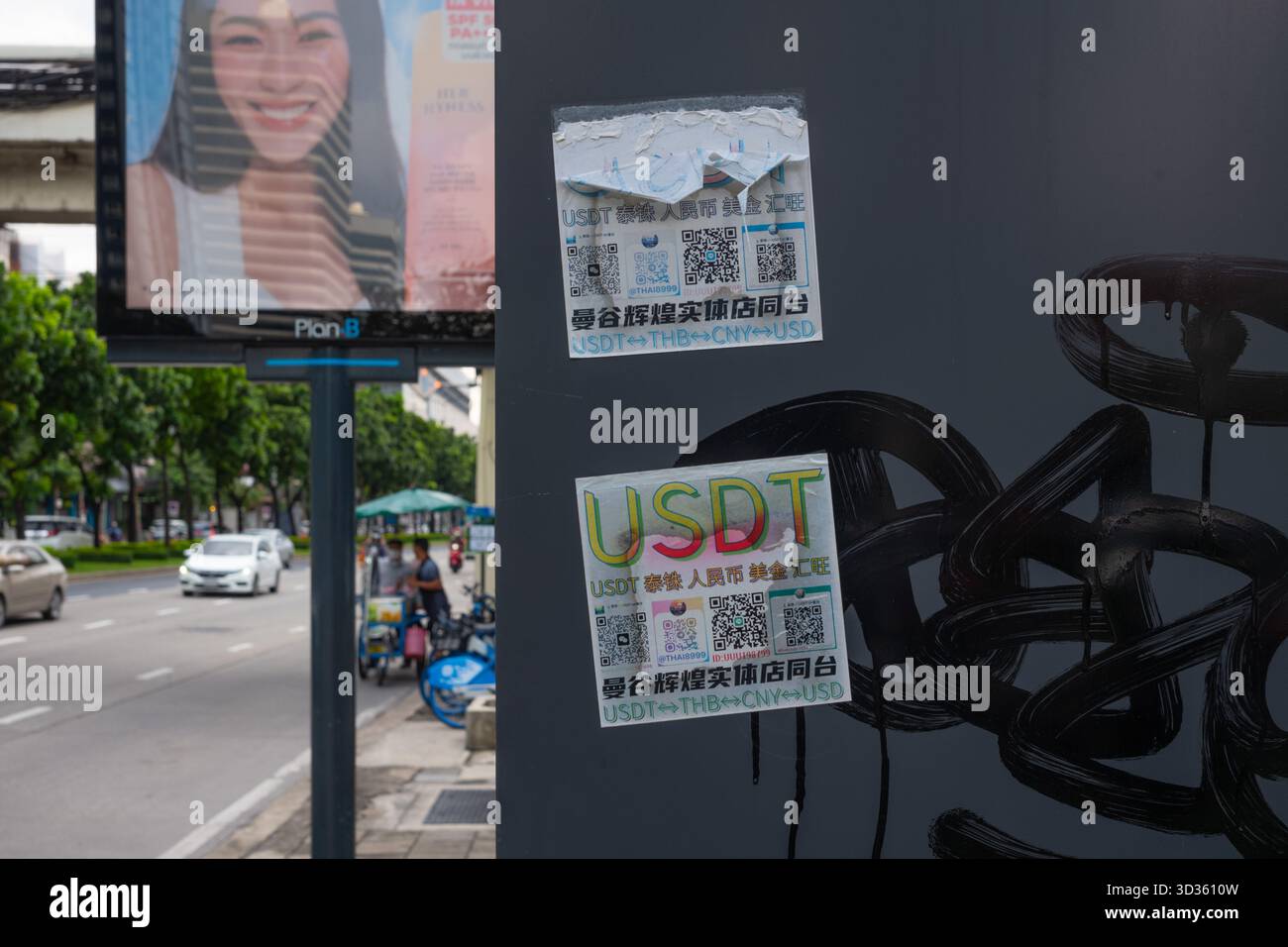 Chinese traders put up stickers of USDT exchanges on a roadside lightbox. Stock Photo