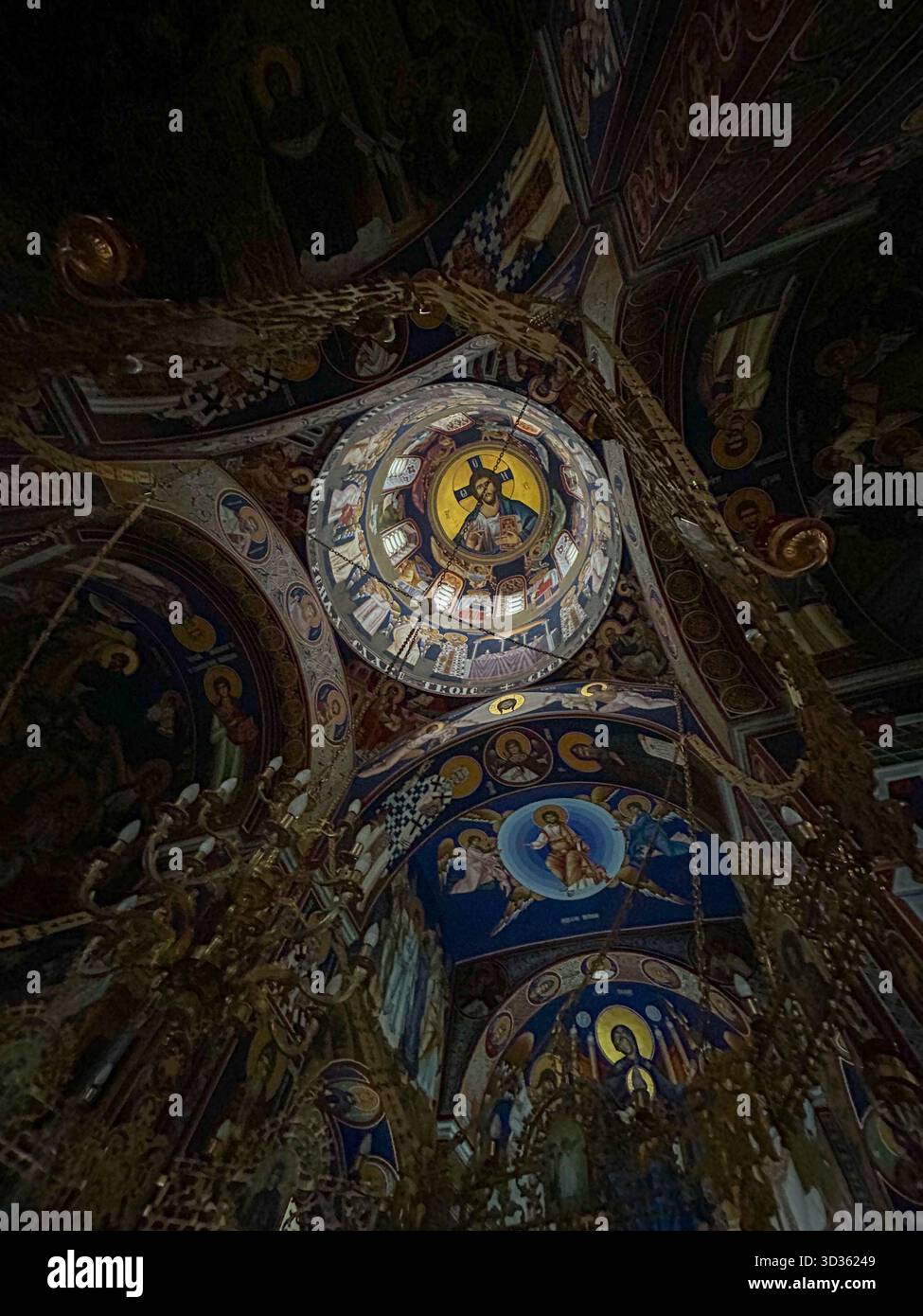 Beautiful Byzantine-style frescoes and ornate chandeliers adorn the dome of a Serbian Orthodox church, featuring Christ Pantocrator and scenes from th - Smartphone Captured Stock Image