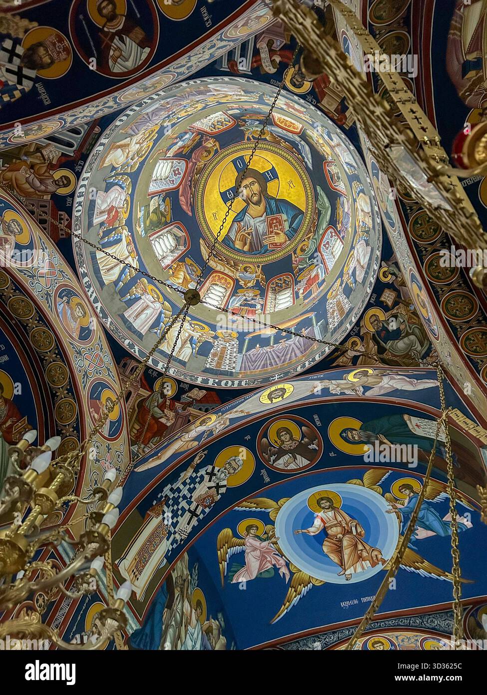Colorful frescoes and golden chandeliers decorate the dome of a Serbian Orthodox church, depicting Christ Pantocrator and biblical scenes in tradition - Smartphone Captured Stock Image