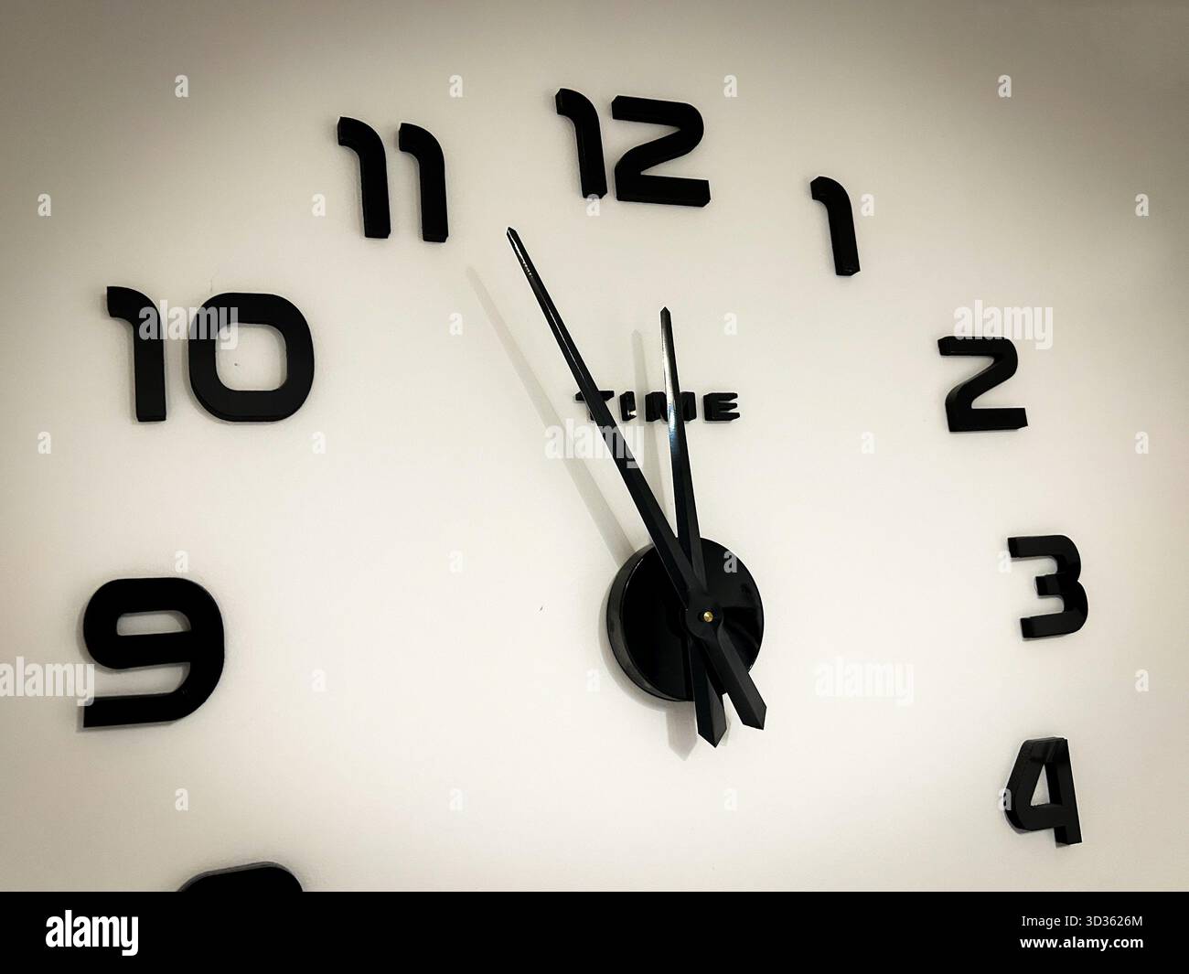 Decorative black wall clock with sleek hands pointing to 11:55, representing the last moment before midnight and the passage of time. - Smartphone Captured Stock Image